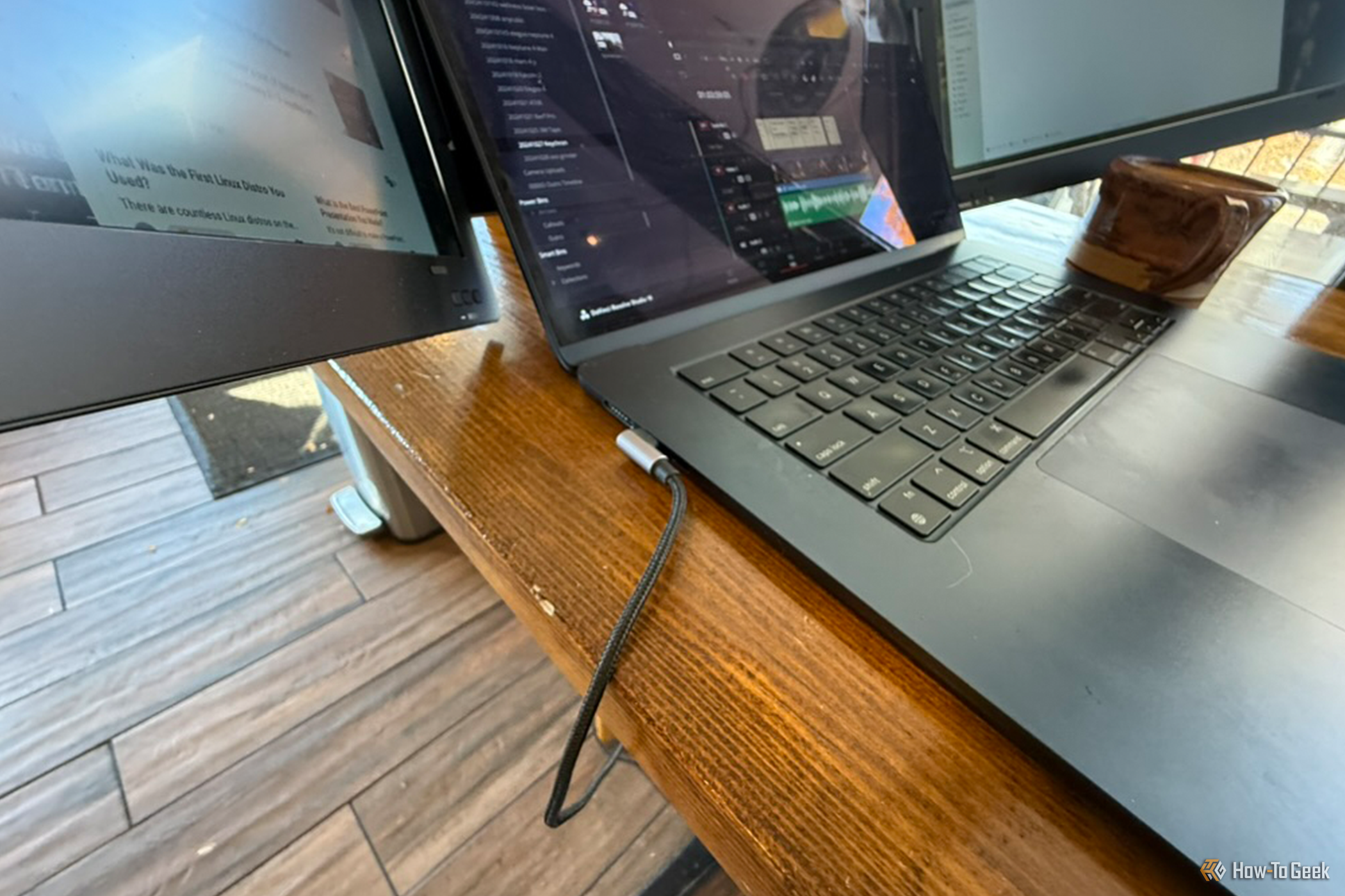 MacBook Air on a wood table with a USB-C cable running from its ports to an external monitor display.