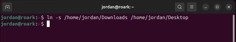 The Linux ln command in a terminal window creating a symlink in the desktop folder to a user's Downloads folder.