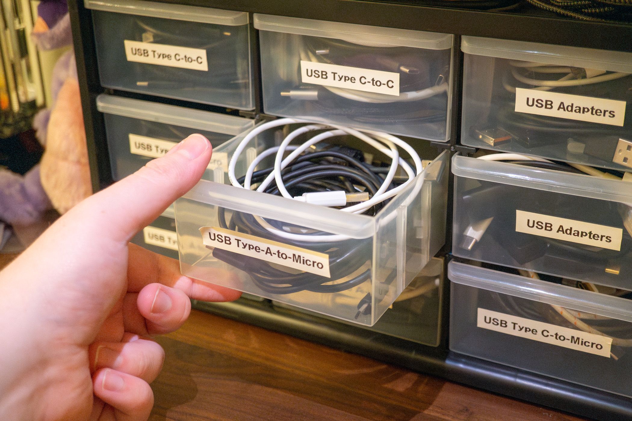 Opening a drawer of USB cables from a plastic cabinet.