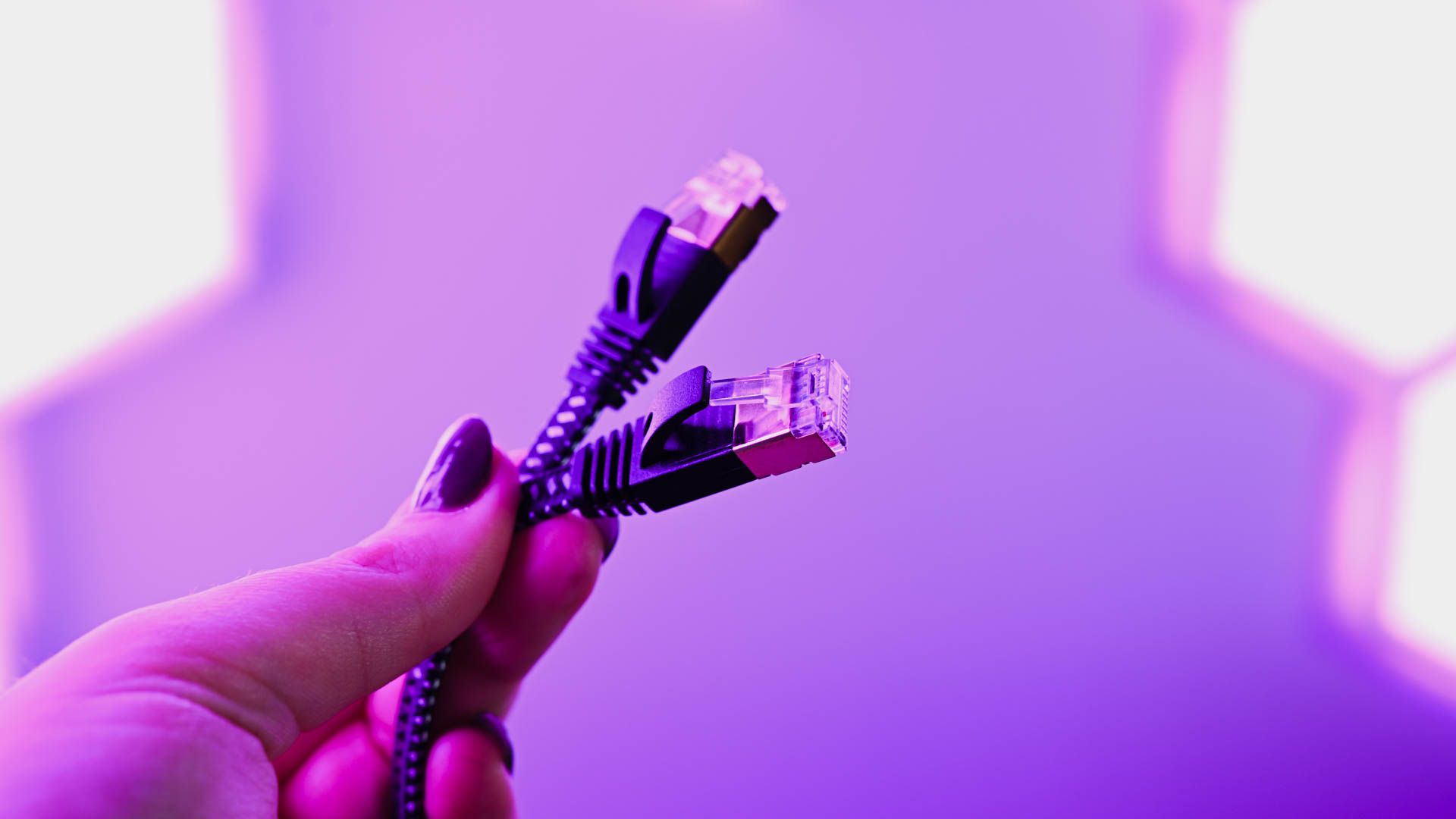 Person holding the CableGeeker ethernet cable for gaming lit by wall leds.