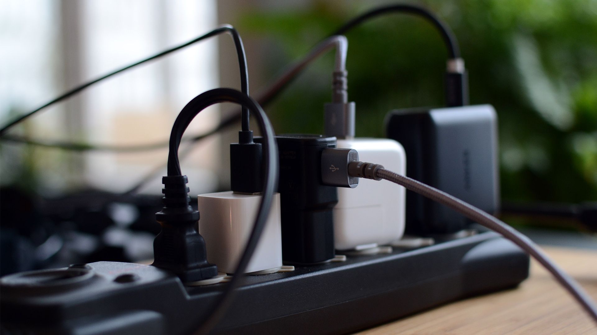 Multiple power adaptors and cables plugged into a power strip.