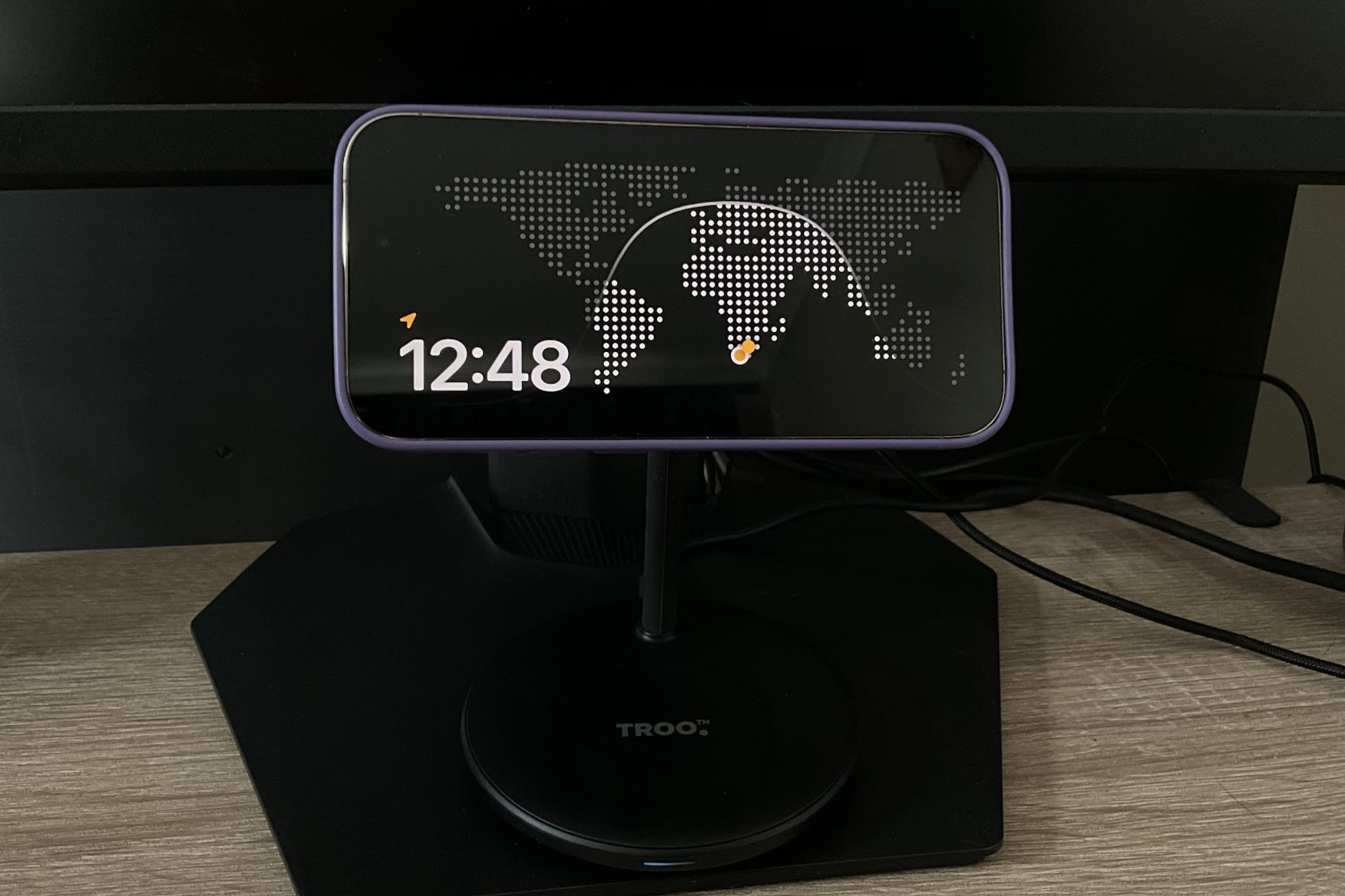 An iPhone 14 Pro in StandBy mode showing all time zones on a map.