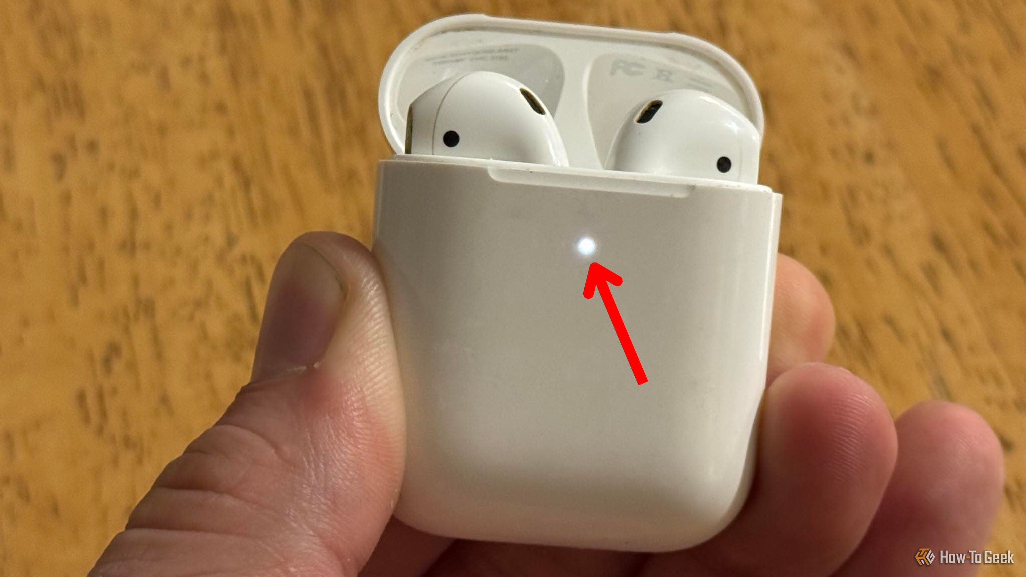 Apple AirPods case open with the pairing mode light illuminated.