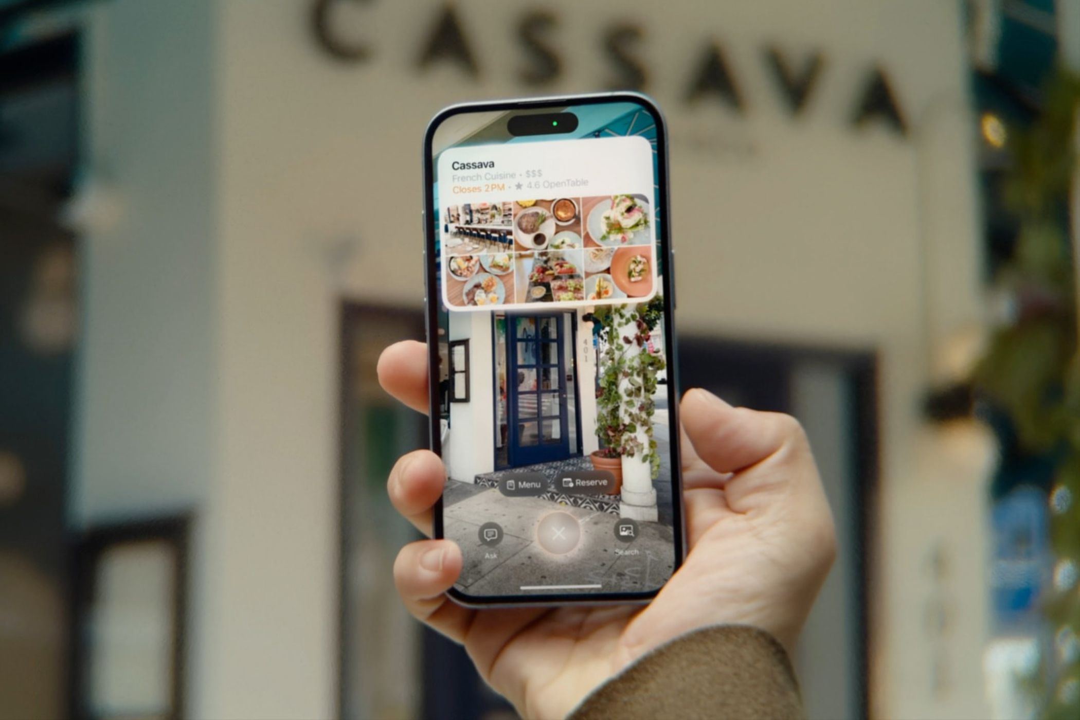 iPhone held in hand, with visual intelligence used to lookup a restaurant in the camera viewfinder.