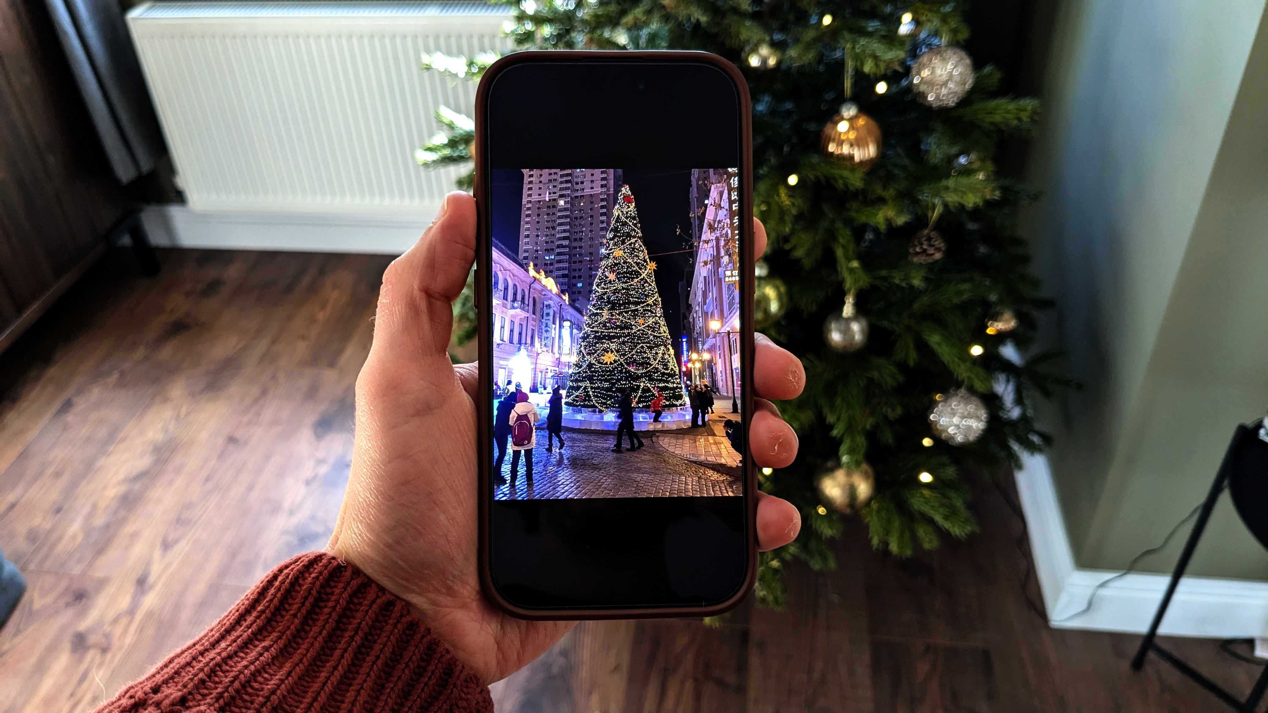 iPhone showing Christmas photos in front of a Christmas tree.