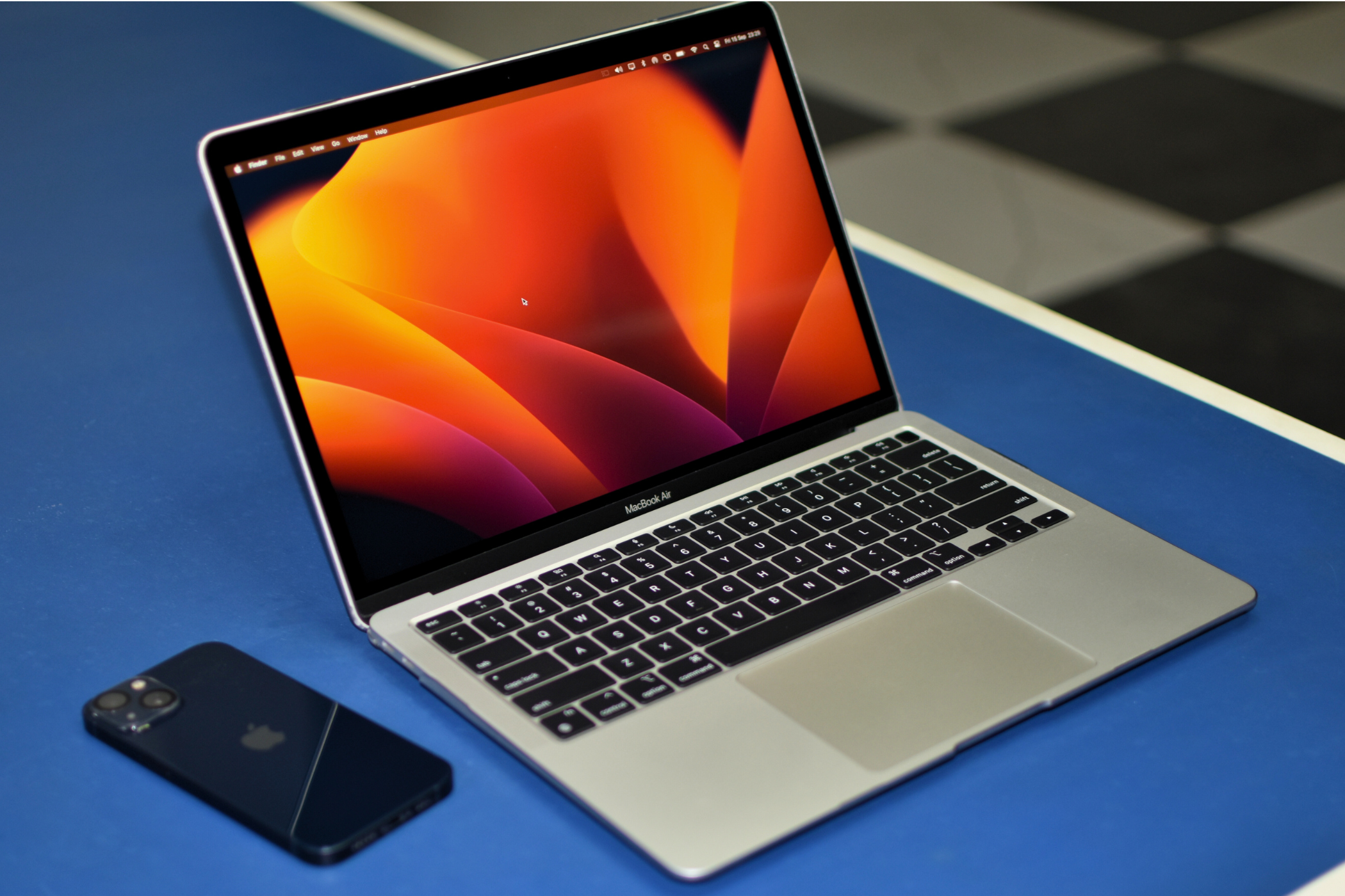 MacBook Air on a blue table with a iPhone to the left