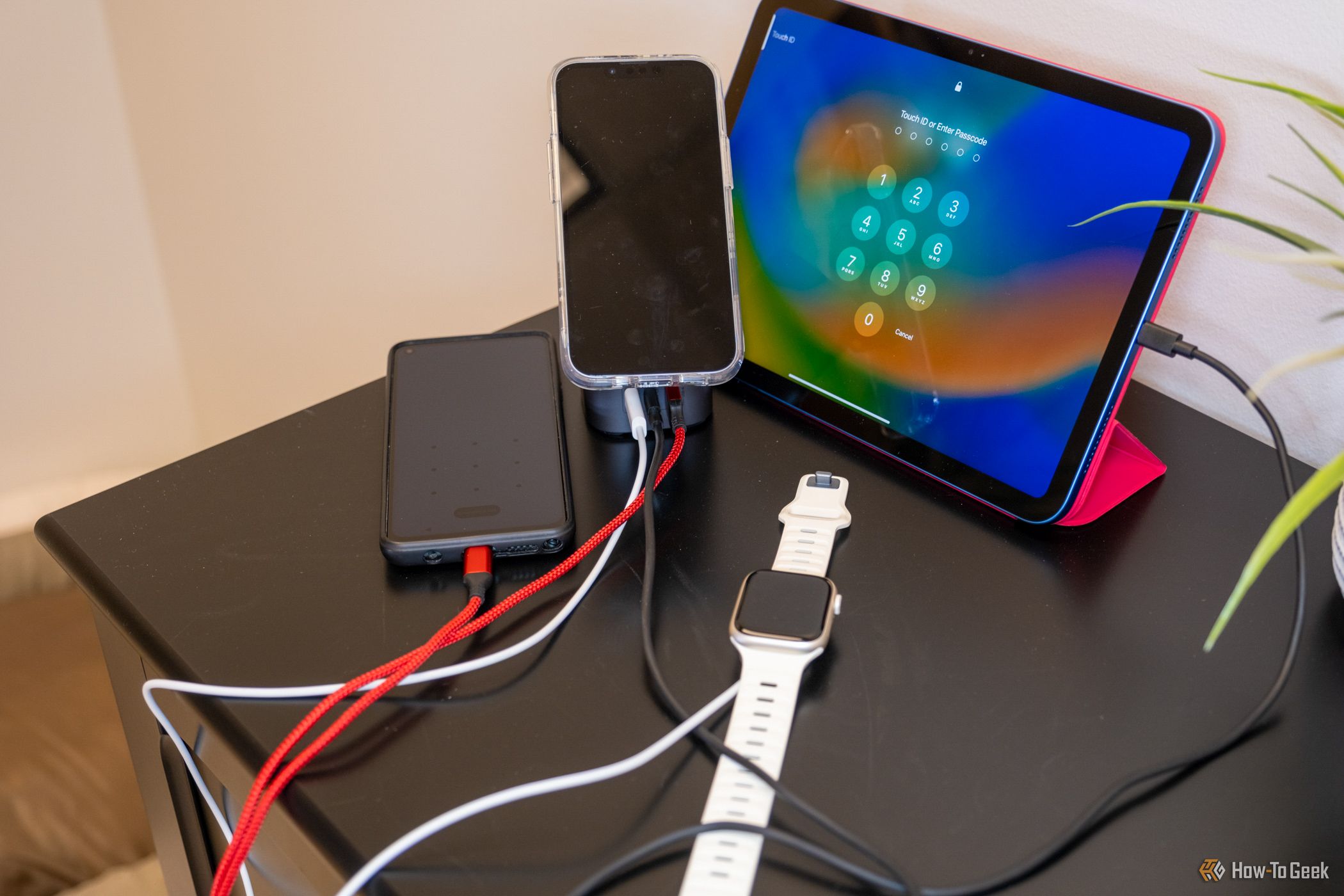 The Ugreen 100W 2-in-1 GaN Charging Station charging a watch, phone, iPad, and battery pack.