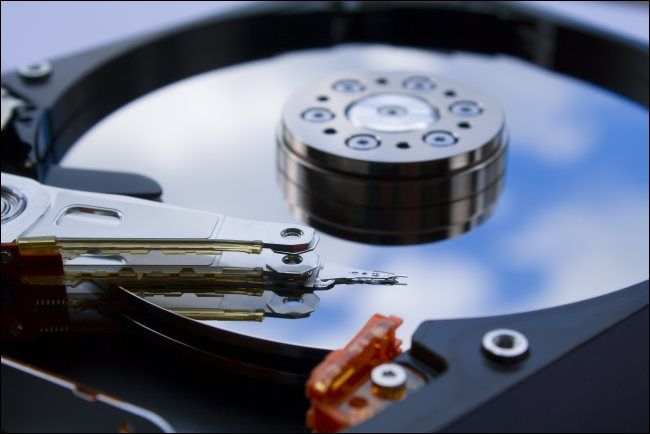 A close-up of a mechanical computer's hard drive platter and head.