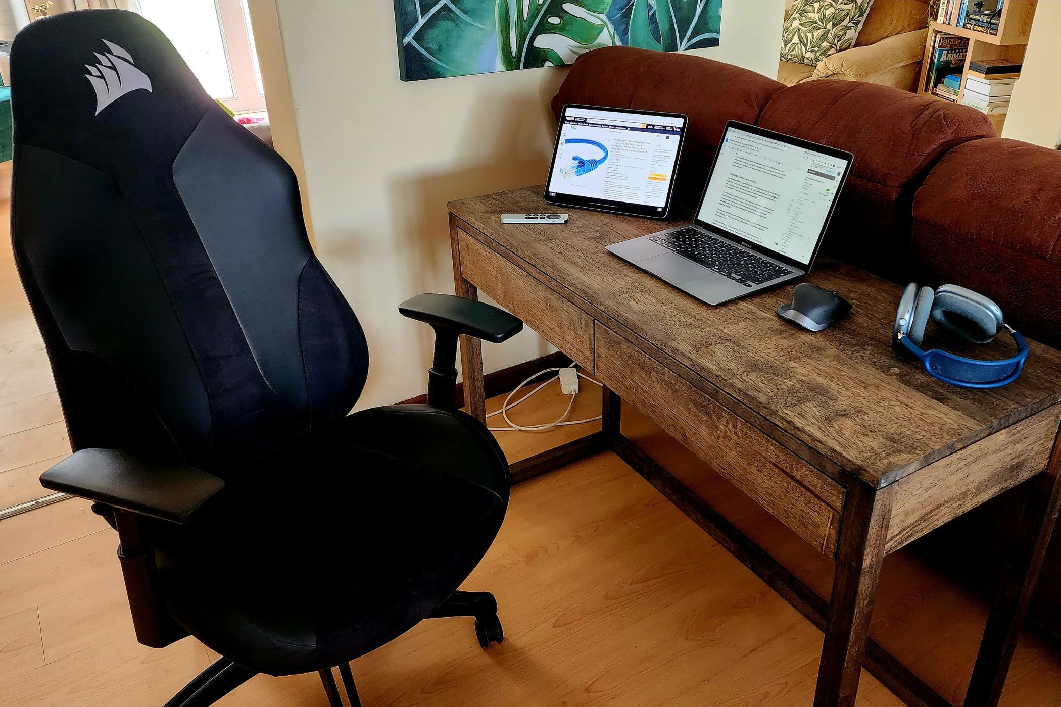 A desk With a MacBook and iPad next to some Airpods Max and an Apple TV Remote