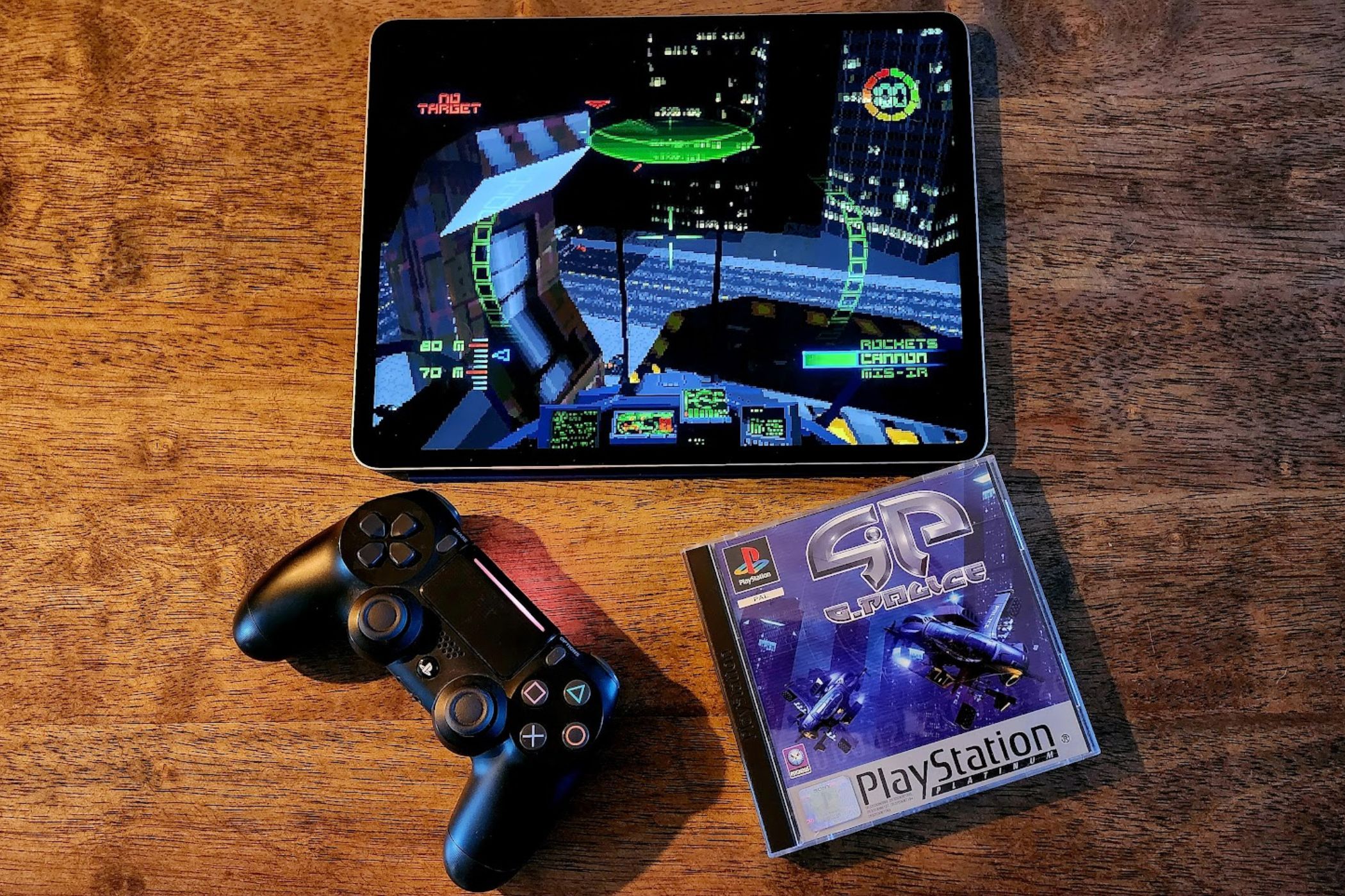 An iPad running G-Police next a physical original copy of the game and a PS4 controller