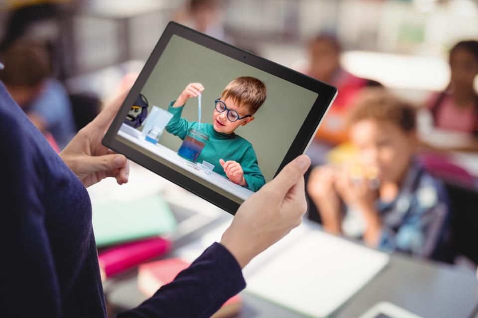 A Women holding an ASUS Chromebook tablet in her hand while in a class.