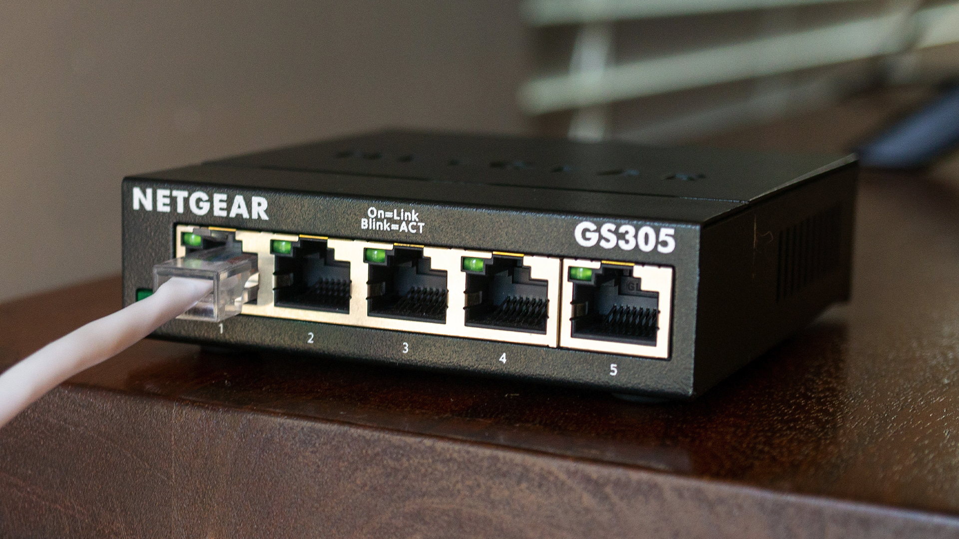 A Netgear 5-port Network Switch with an Ethernet cable attached.