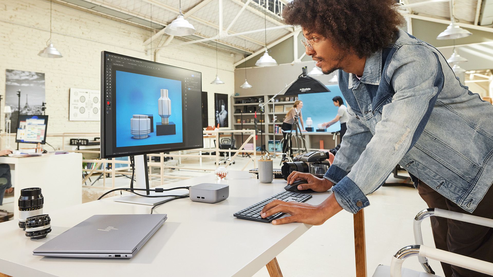 Person using a keyboard and monitor at a desk, connected to a laptop through a small HP dock.