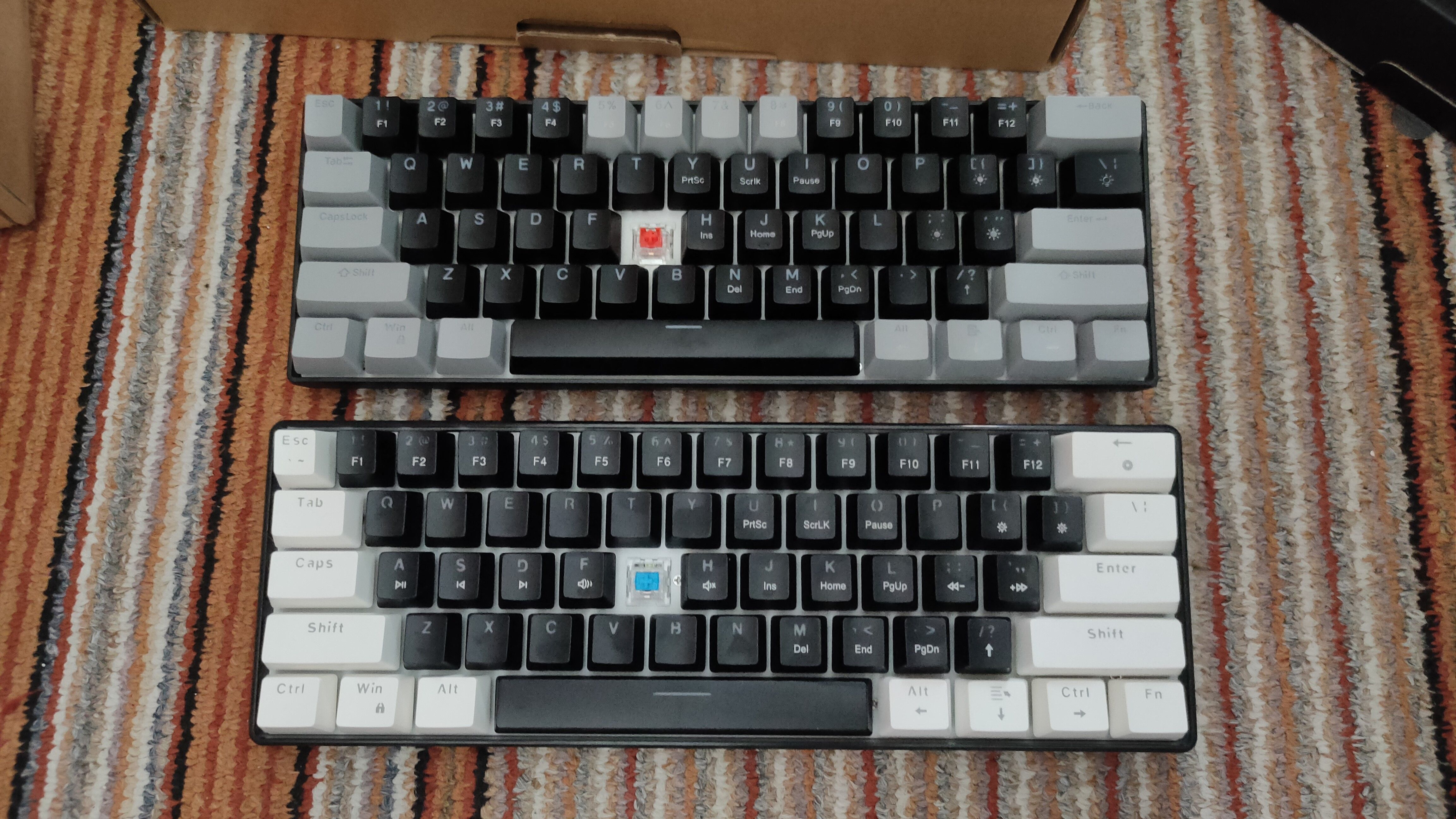 Two 60% mechanical keyboards with red and blue switches, with the G keycap removed.