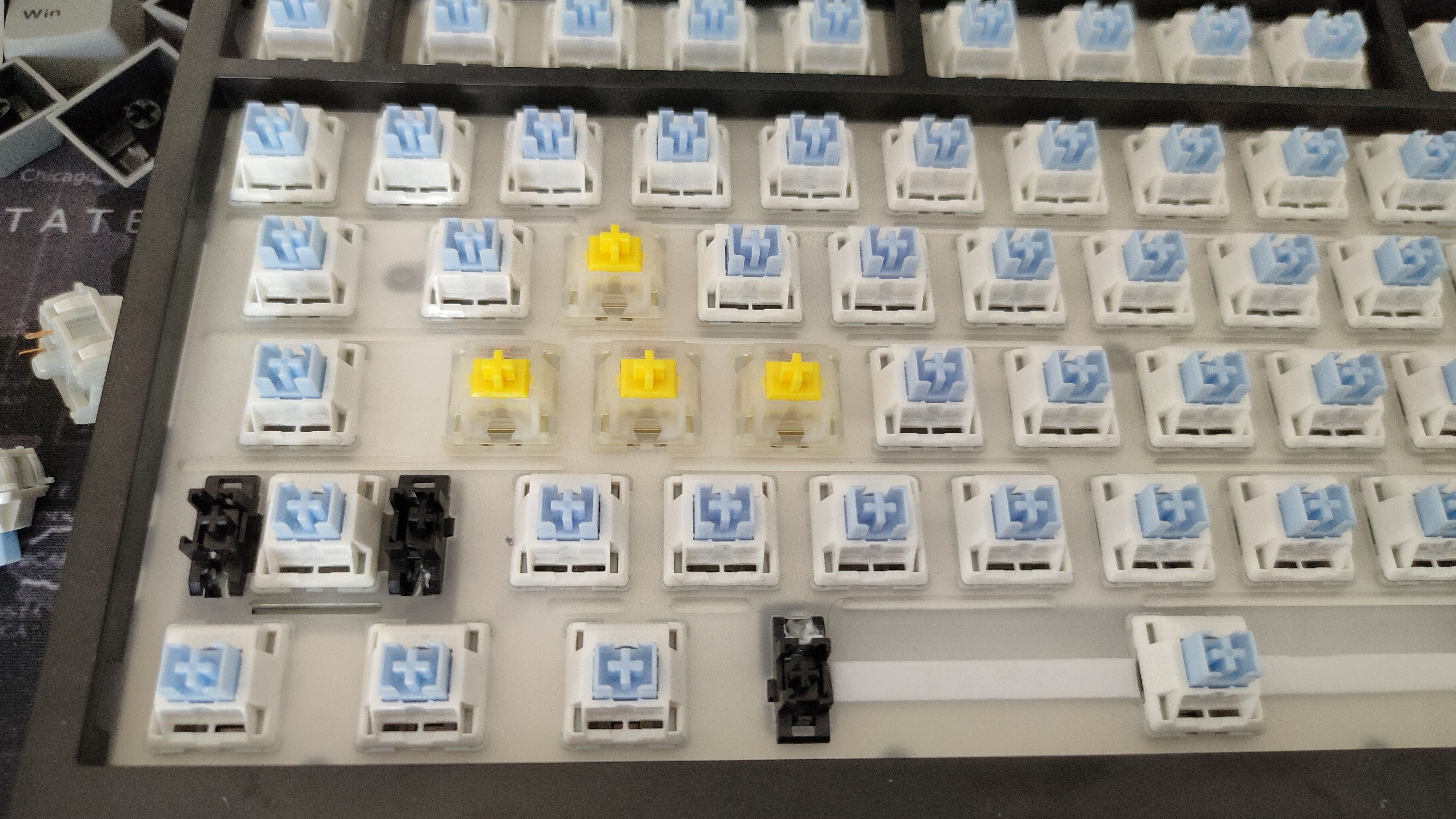 A keyboard with the keycaps removed and a few Gateron yellow switches in place of the WASD keys.