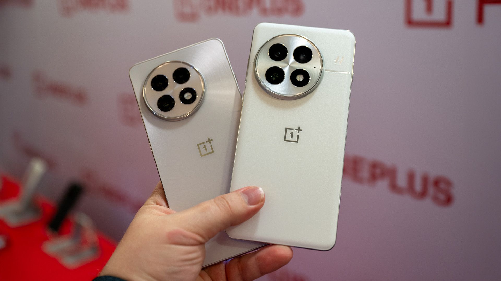 Person holding the OnePlus 13 and 13R in white.