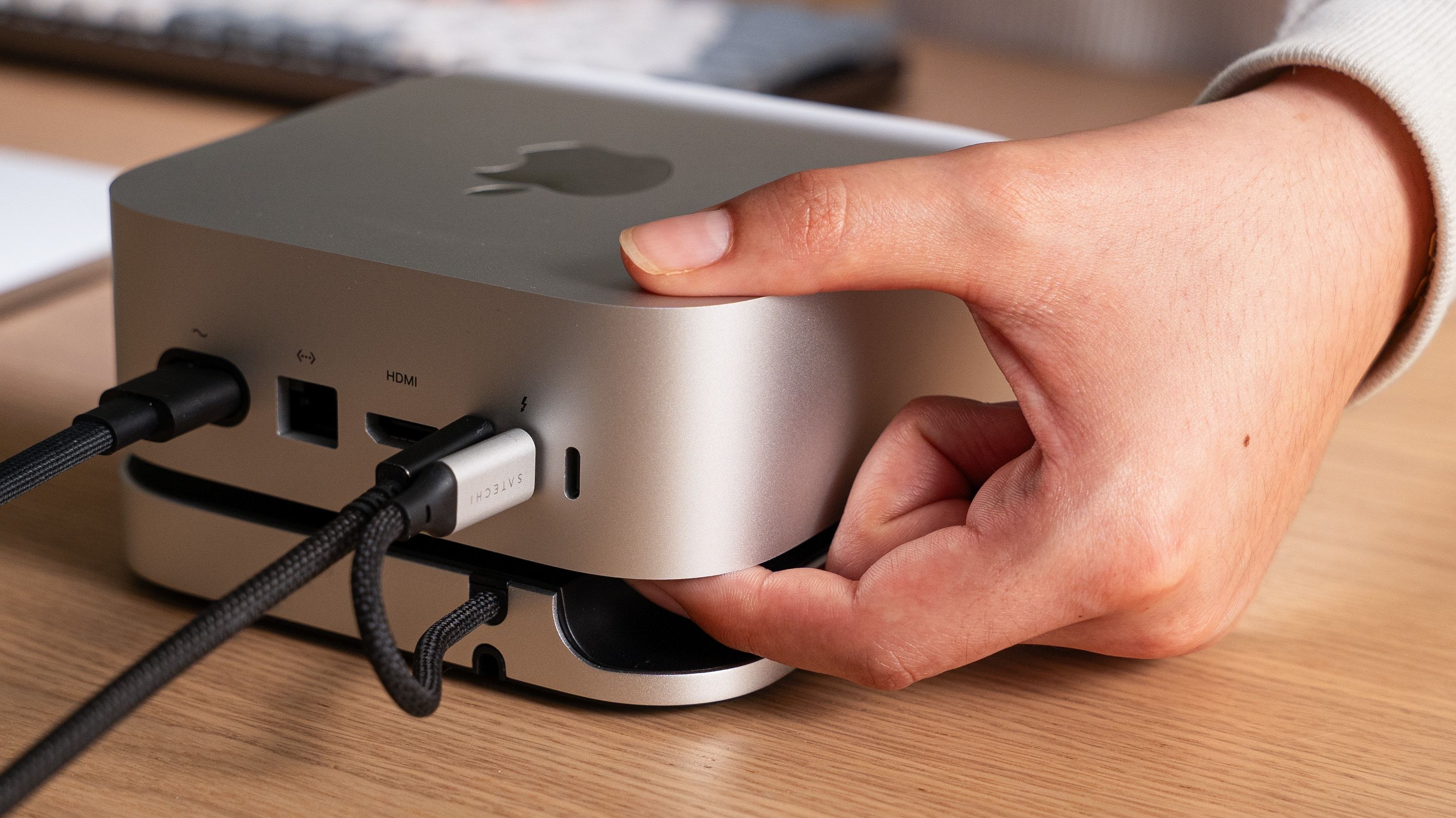 Hand reaching for the power button on Satechi's Mac Mini hub.