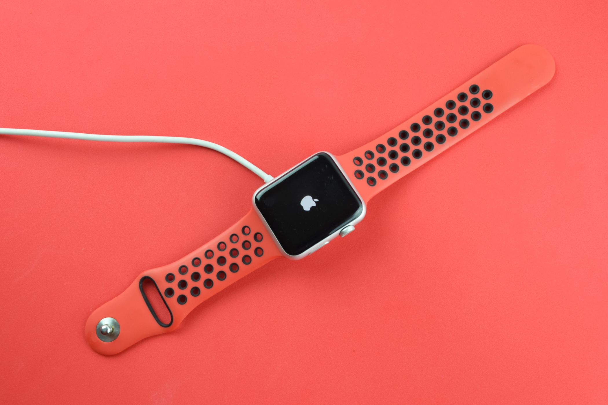 Apple Watch connected to a charger displaying the Apple logo.