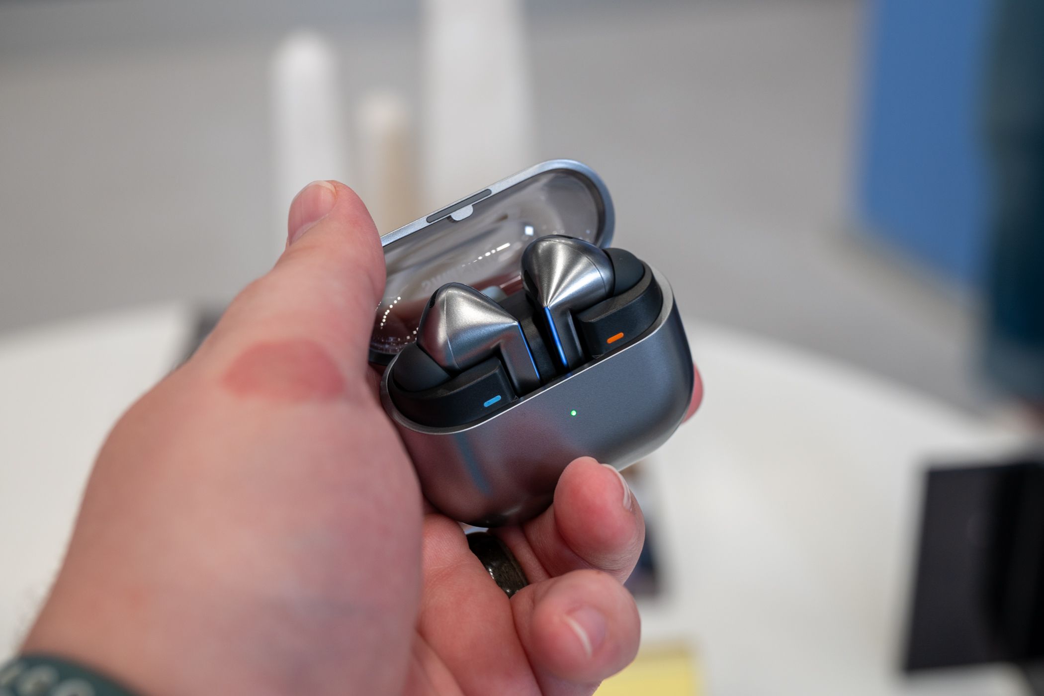 Person holding the Samsung Galaxy Buds 3 Pro inside their charging case with the lid open.