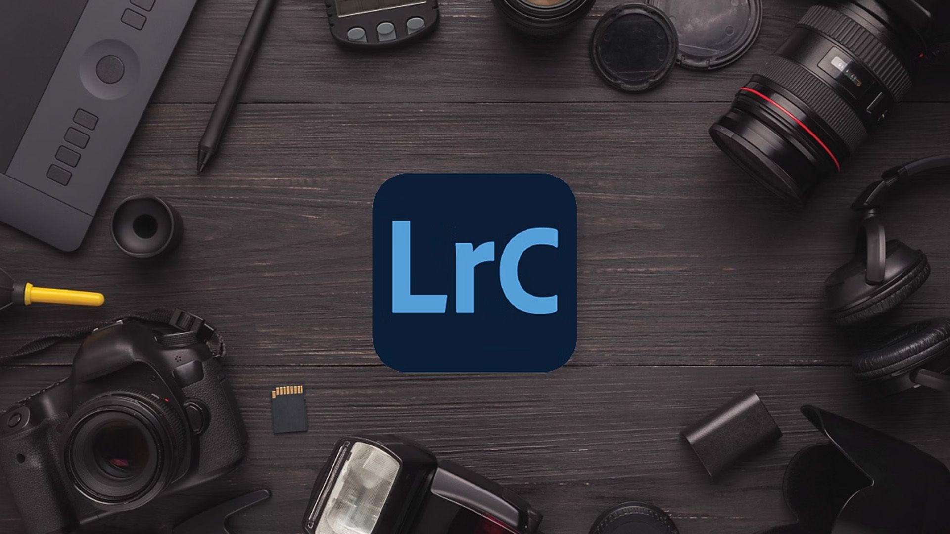 The Adobe Lightroom Classic logo placed on a table surrounded by cameras and accessories.