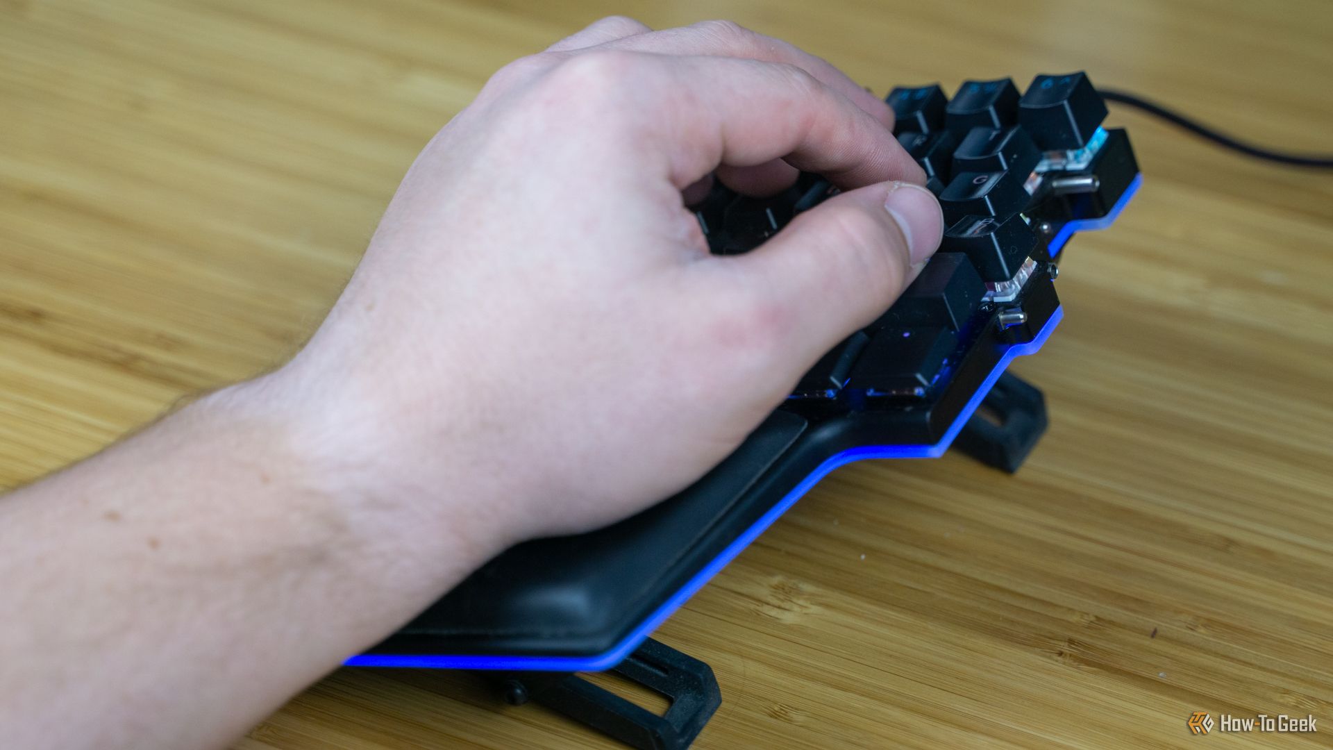 A person's hand resting on the left half of the Dygma Raise keyboard.