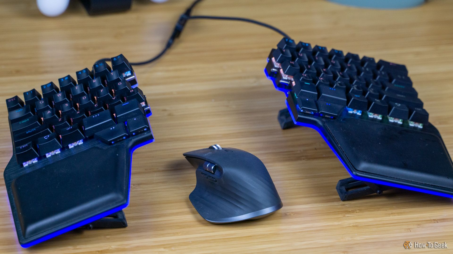 The Dygma Riase keyboard sitting on a desk with a mouse between the halves.