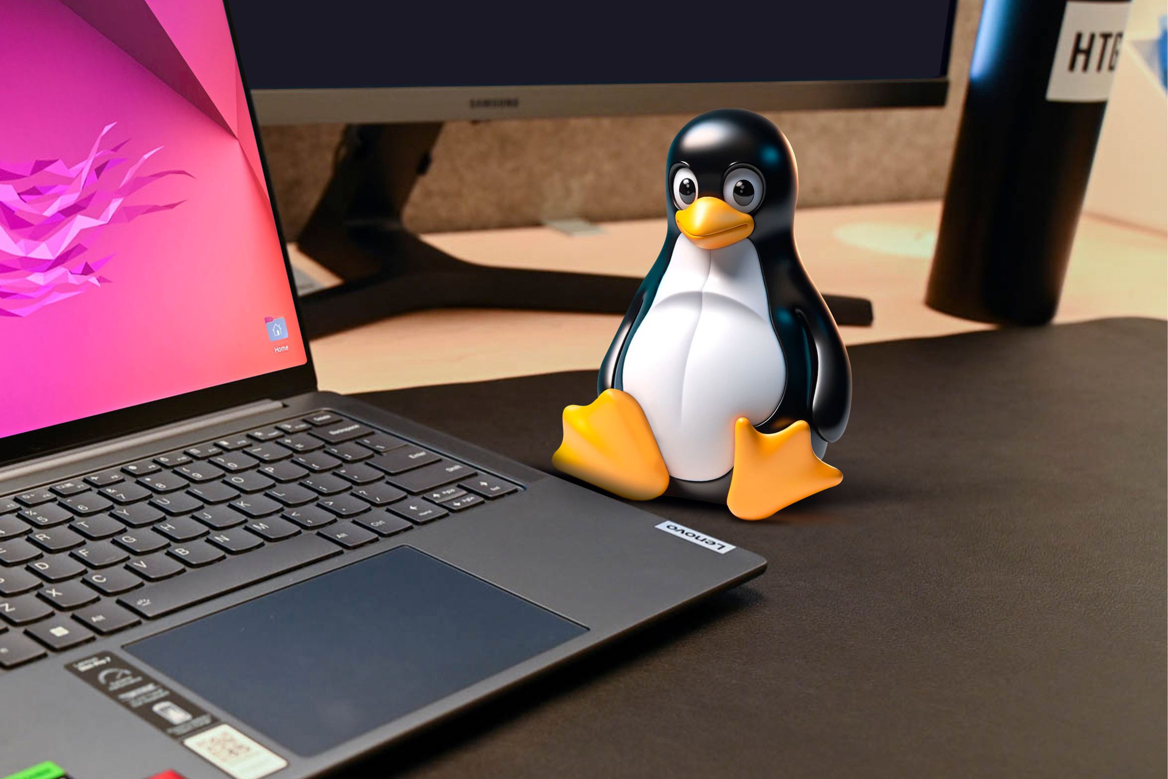 Linux mascot on a desk next to a laptop.