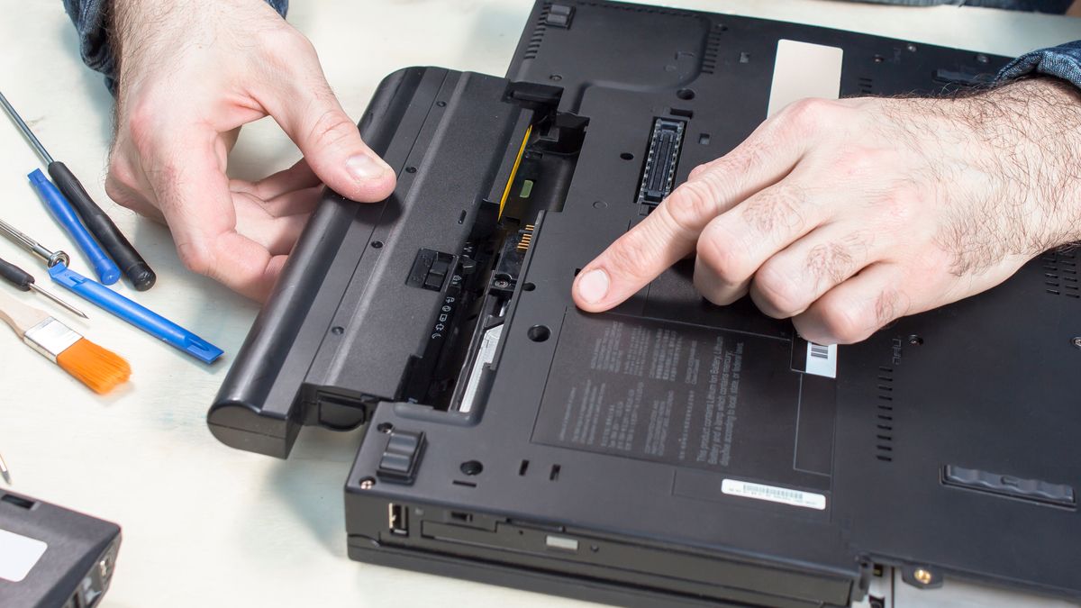 Person checking and removing the battery from a laptop.