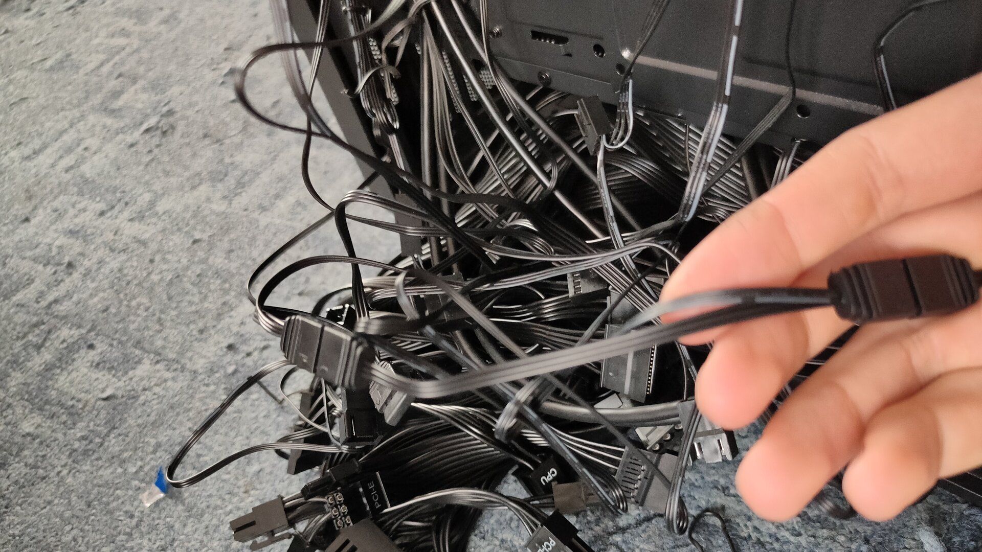 A mess of black computer cables sticking out of a computer case.