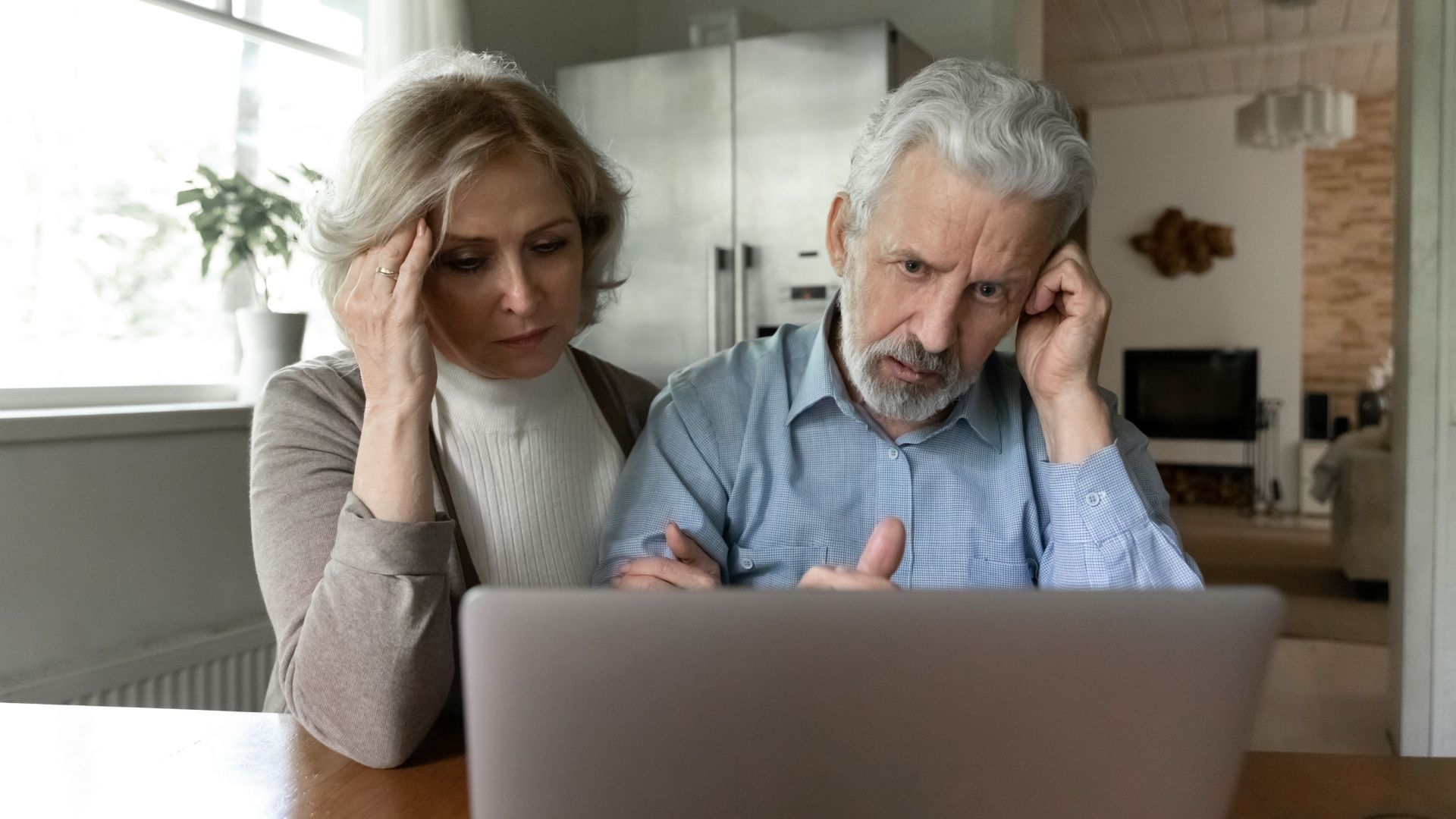 Upset 60s senior couple using laptop together at home