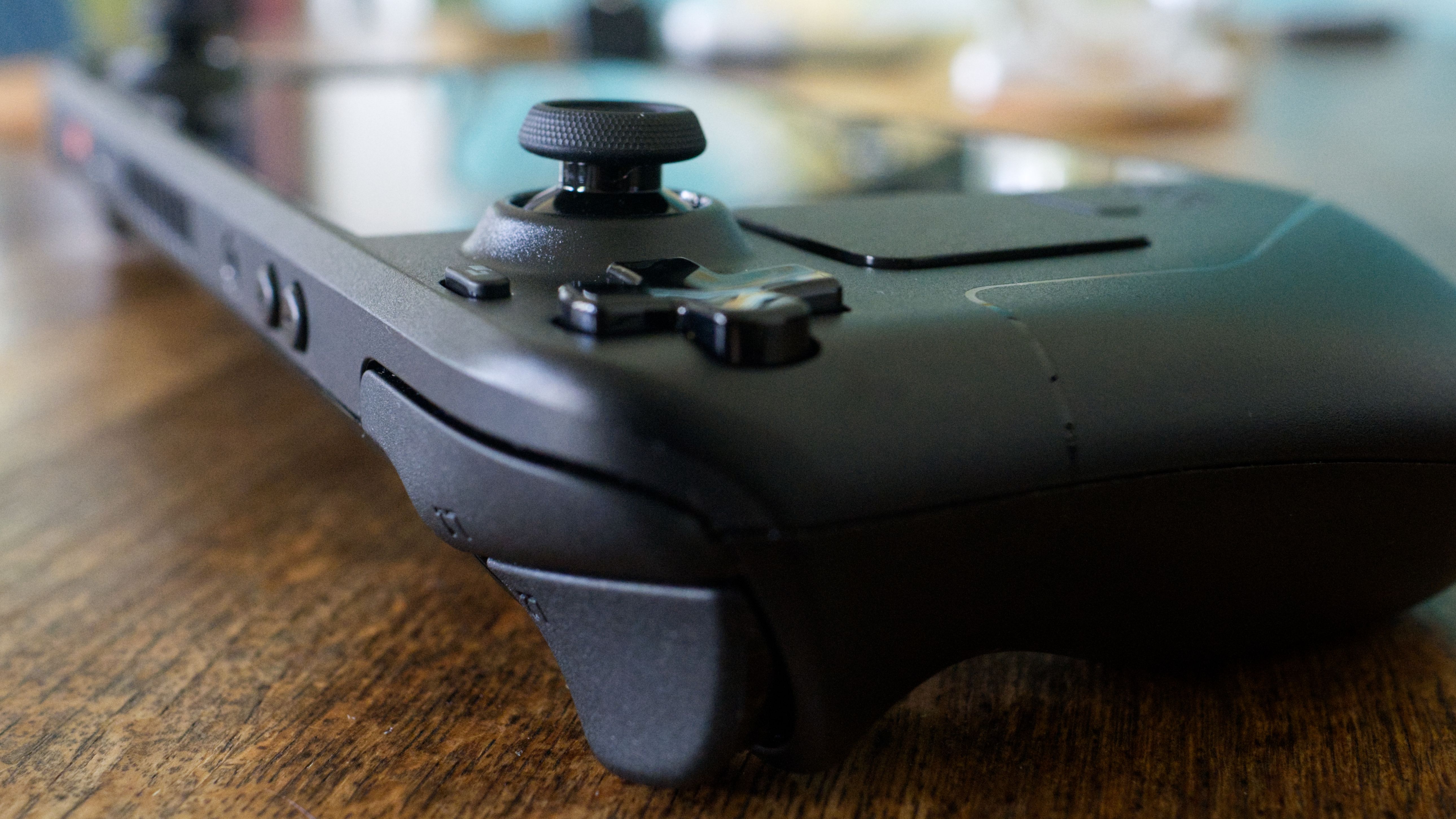 Steam Deck on a wooden table with the left analog stick in sharp focus.