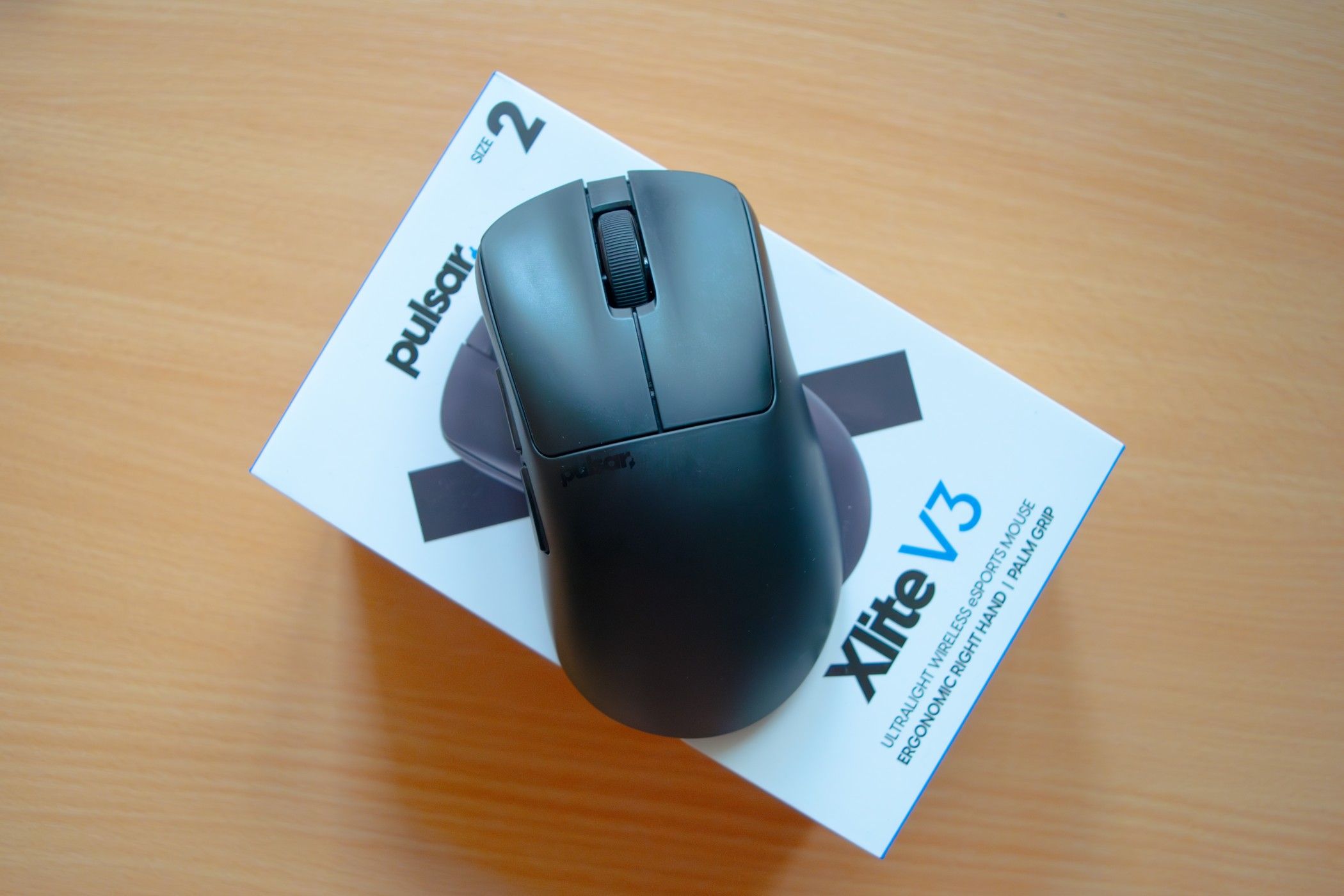 A Pulsar Xlite V3 mouse laying on top of the box it comes in.