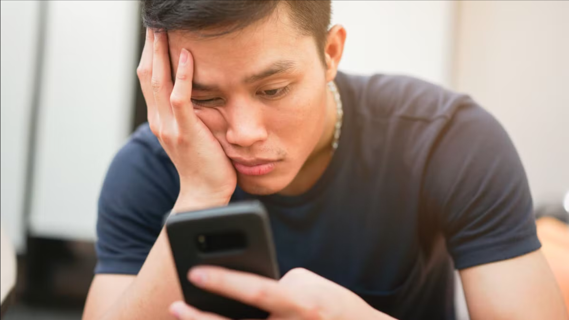 A person scrolling on a phone with a bored look on their face.