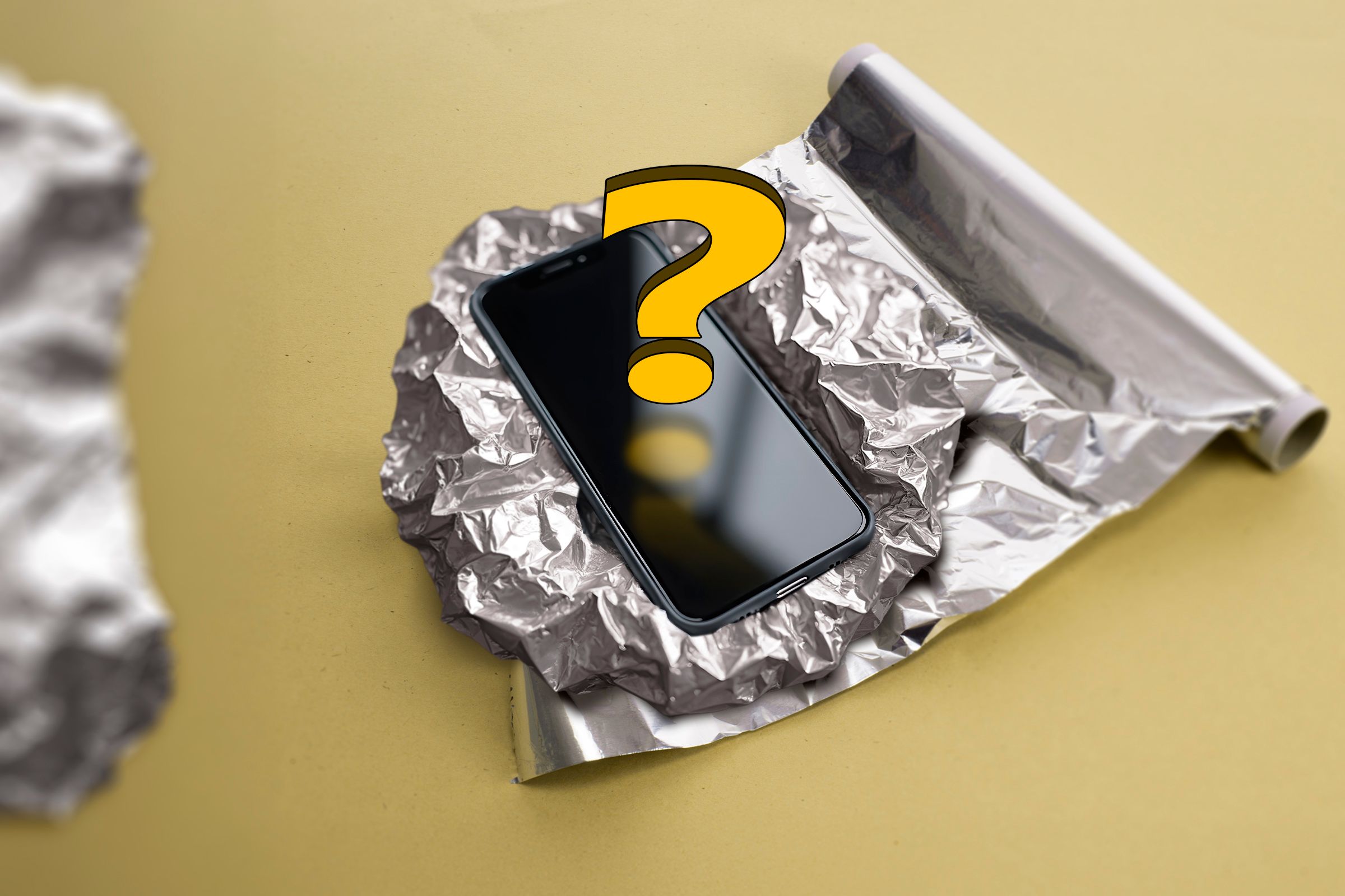 A phone in aluminum foil with a question mark above the screen.