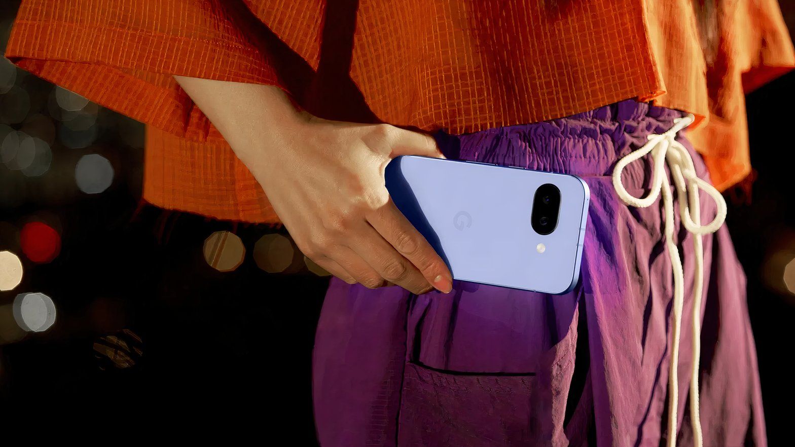 Closeup of a woman holding a Google Pixel 9a phone at waist height.