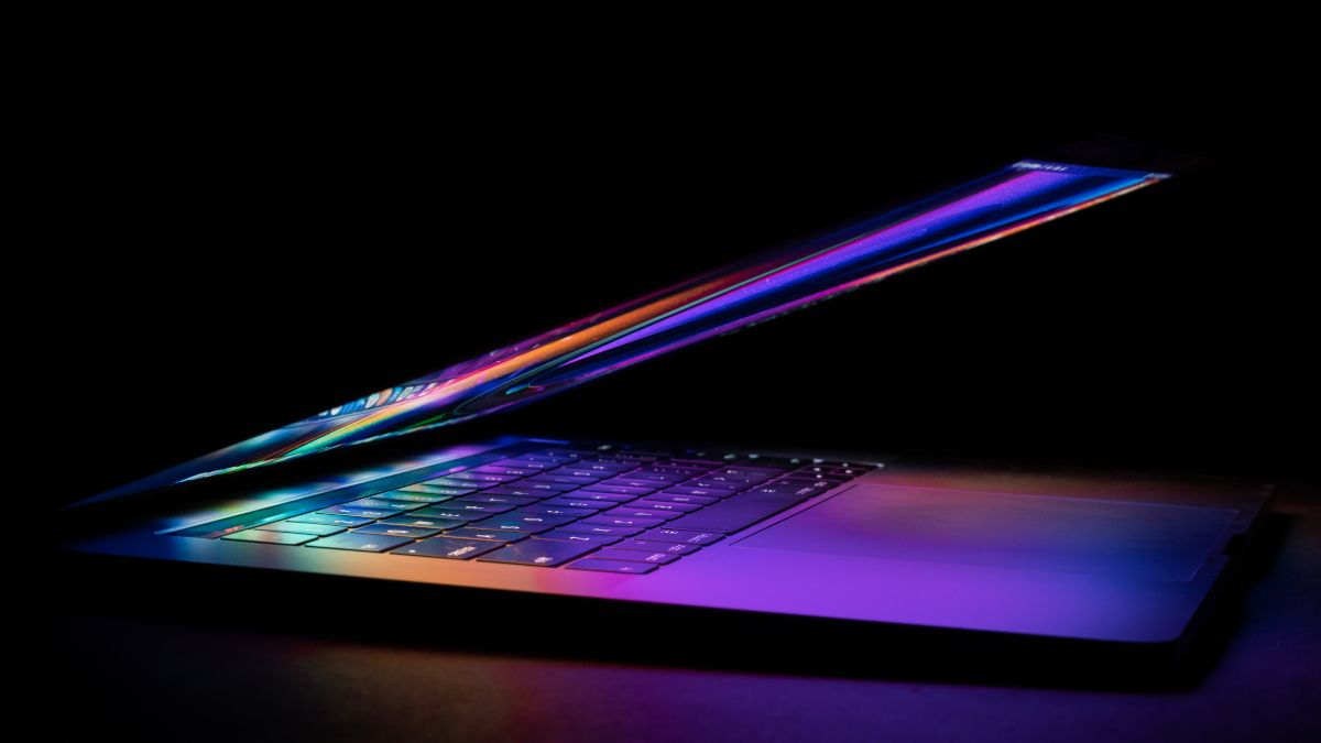 A half-closed MacBook with bright colors from the screen reflected on the keyboard.