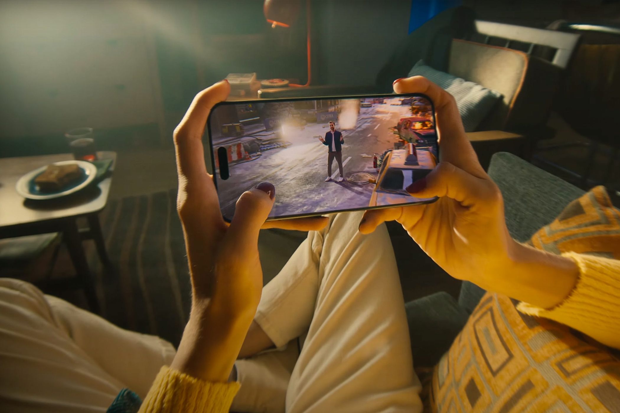 A person holding an iPhone 15 Pro, playing video games.