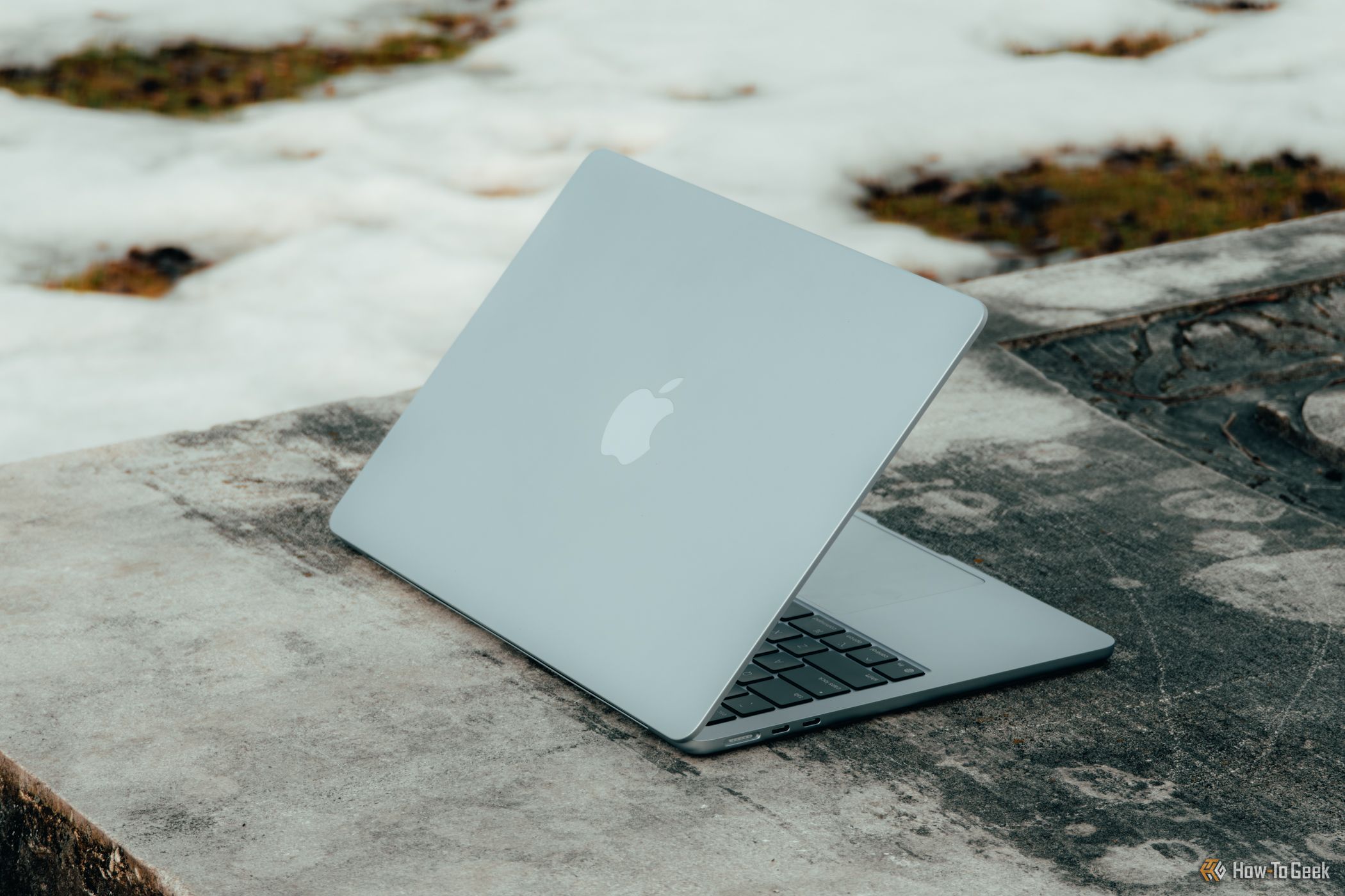 M4 MacBook Air in Sky Blue angled on concrete bench.