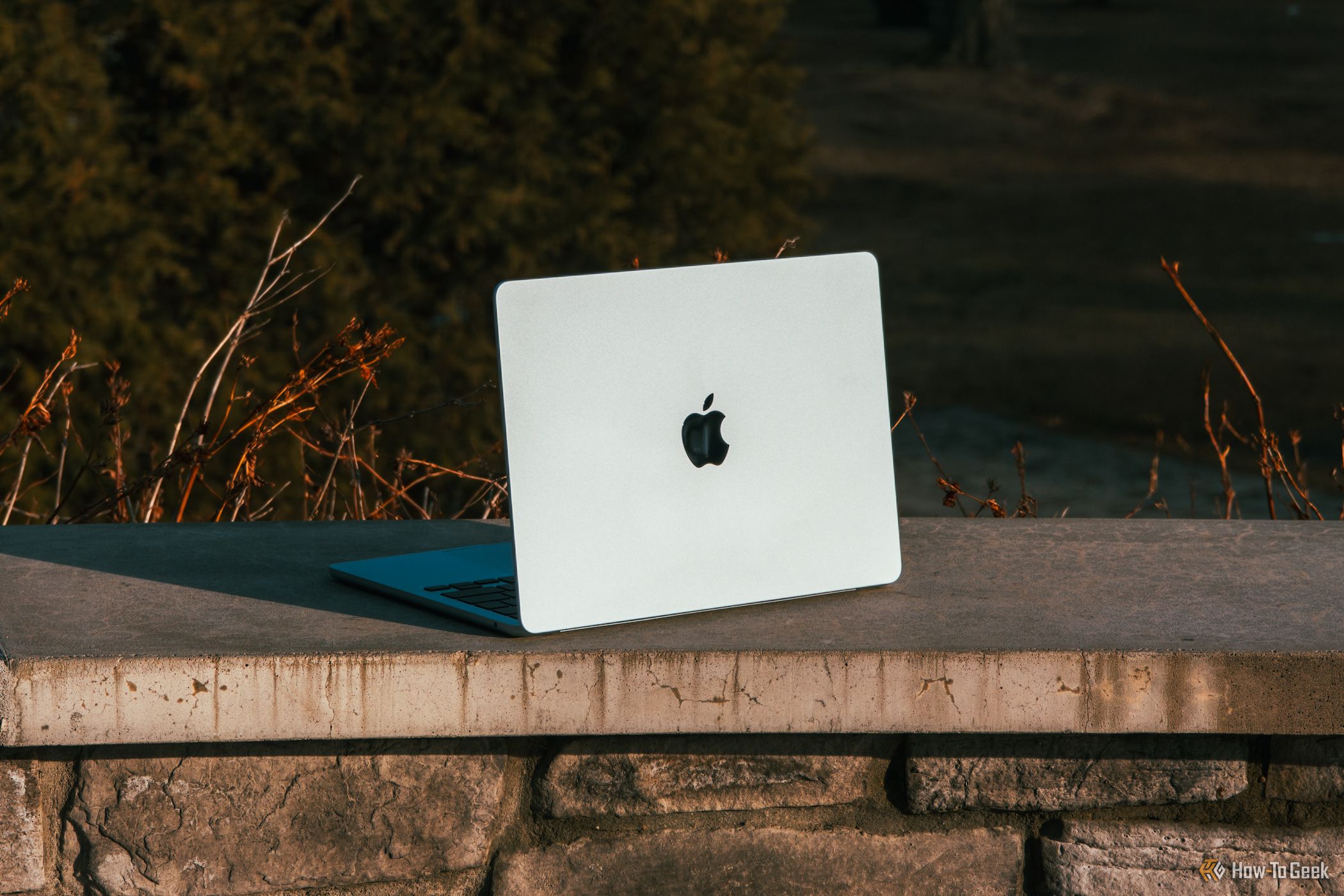 M4 MacBook Air in Sky Blue angled on concrete ledge against sunlight.