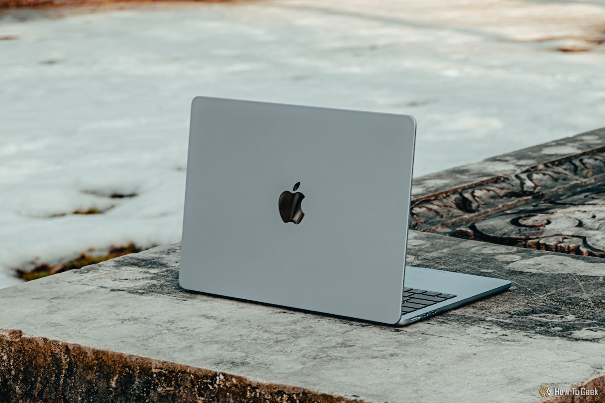 M4 MacBook Air in Sky Blue from an angle on concrete bench.