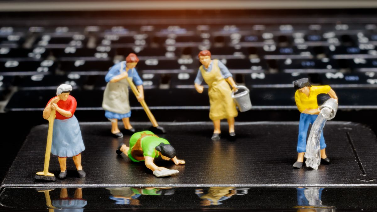 Plastic figures cleaning a laptop.