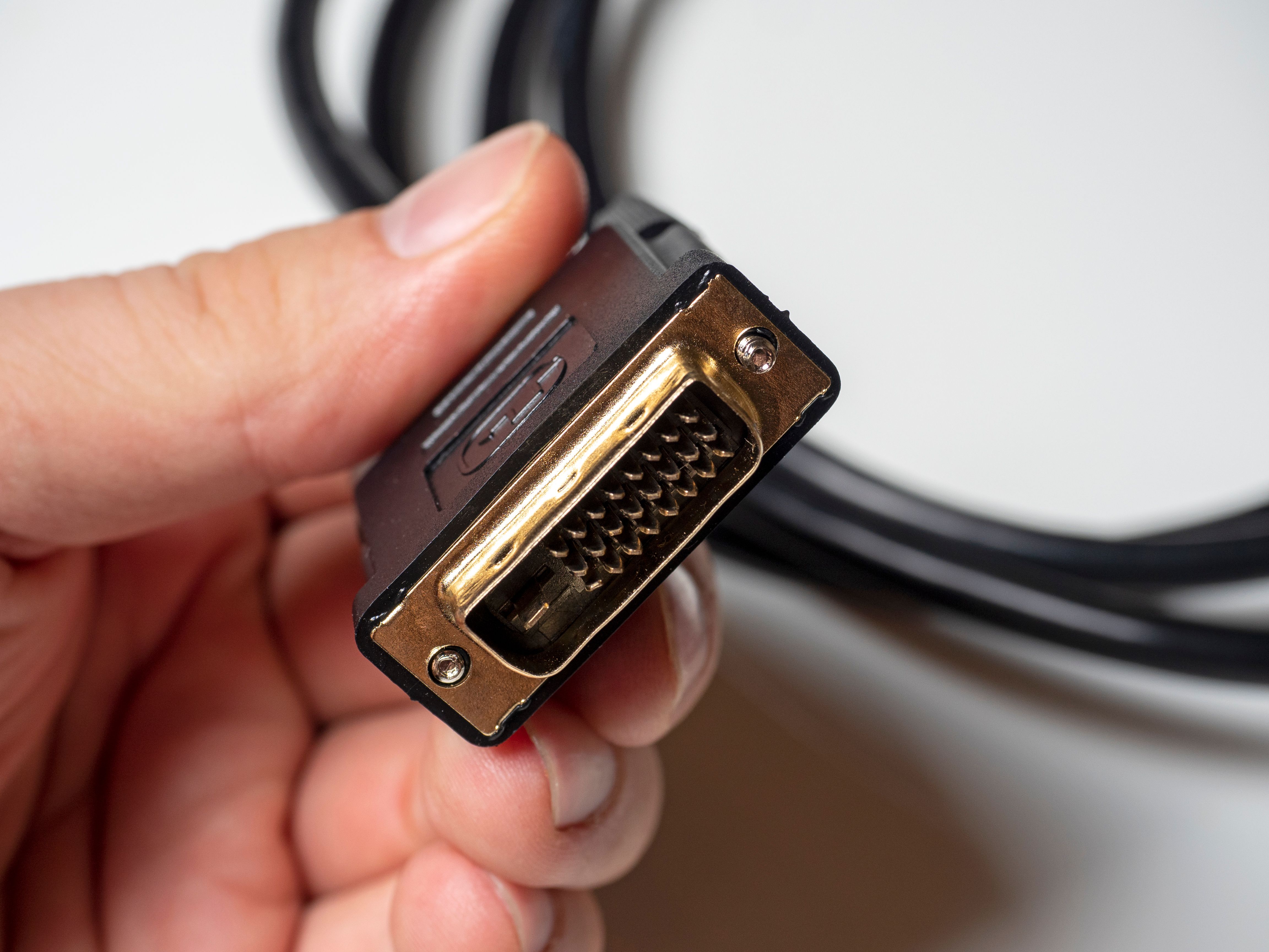 A hand holding a DVI cable.